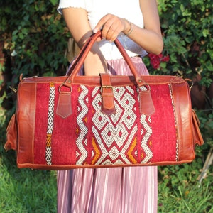 May include: A red and brown leather travel bag with a geometric pattern. The bag has a top handle and a shoulder strap.