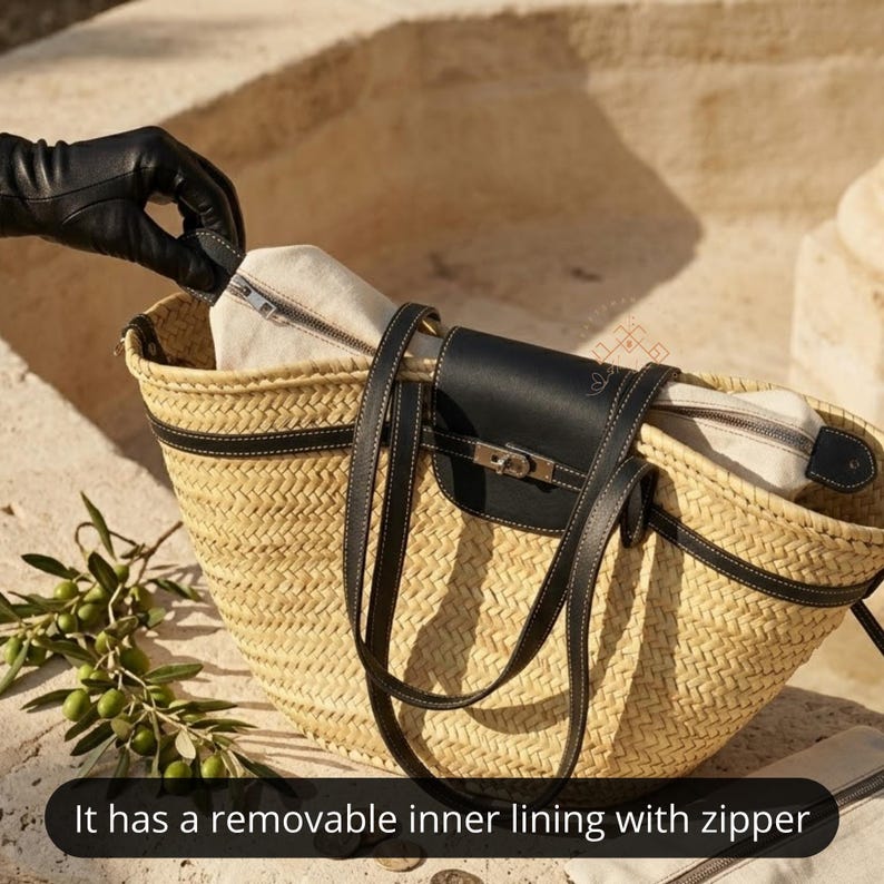 May include: A woven straw tote bag with black leather detailing. The bag has a black leather flap with a silver clasp and long black leather straps. It has a removable inner lining with a zip. A gloved hand is unzipping the inner lining.