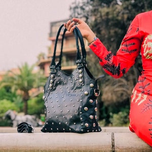 May include: A black leather handbag with silver studs. The bag has a top handle and a shoulder strap.