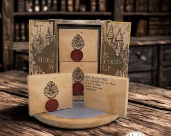 May include: A handmade wooden box with a map of Hogwarts and the text "The Marauders Map" on the front. The box is open and contains three smaller boxes with the Hogwarts crest and a wax seal. The smaller boxes have the text "Mr. H Potter, The Cupboard under the Stairs, 4 Privet Drive, Little Whinging, Surrey" on the front.