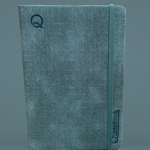 Puede incluir: Un cuaderno gris cubierto de tela con un cierre de banda el&aacute;stica negra y la palabra "Quidebook" impresa en la portada.