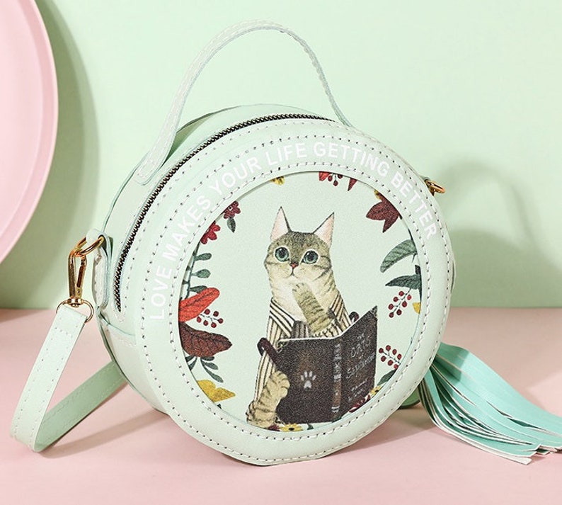 May include: A light green round purse with a cat illustration and the text 'Love makes your life getting better'.