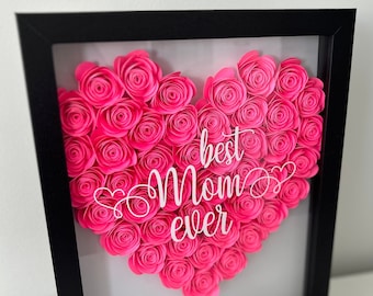Könnte beinhalten: Ein gerahmtes Herz aus rosa Papierrosen mit dem Text "best mom ever" in weißen Buchstaben.