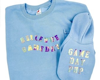 Può includere: Felpa azzurra e felpa con cappuccio abbinata per cani. La felpa ha la scritta "BELLEVUE GAMEDAY" in lettere iridescenti. La felpa con cappuccio per cani dice "GAME DAY PUP" in lettere iridescenti.