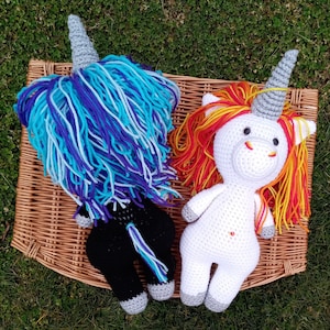 May include: Two crocheted unicorn toys. One is black with blue and purple yarn for the mane and tail. The other is white with a rainbow mane and tail.