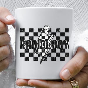 May include: White ceramic mug with a black and white checkered pattern and a lightning bolt graphic. The text "Radiology" is printed in black on the mug.