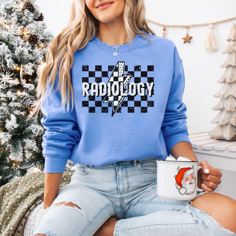 May include: A blue sweatshirt with a black and white checkered pattern and a lightning bolt graphic. The text "RADIOLOGY" is printed in white on the checkered pattern.