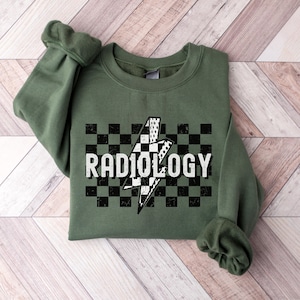 May include: A green sweatshirt with a black and white checkered pattern and a lightning bolt graphic. The text "RADIOLOGY" is printed in white on the checkered pattern.