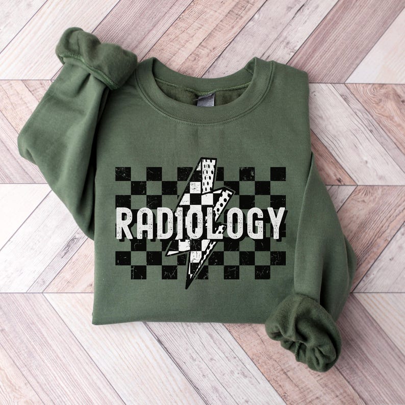 May include: A green sweatshirt with a black and white checkered pattern and a lightning bolt graphic. The text "RADIOLOGY" is printed in white on the checkered pattern.