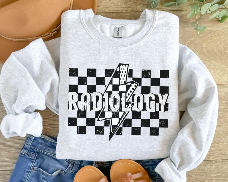 May include: A gray sweatshirt with a black and white checkered pattern and a lightning bolt graphic. The text "RADIOLOGY" is printed in black on the checkered pattern.
