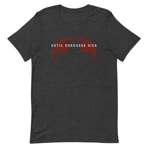May include: Dark heather grey t-shirt with a red graphic of two wings and the text "Until Darkness Dies".