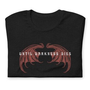 May include: Black t-shirt with a red graphic of two wings and the text "UNTIL DARKNESS DIES" in white.
