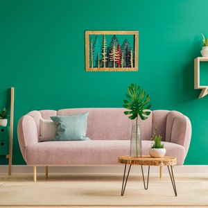 May include: A pink sofa with a blue and white throw pillow sits in a living room with a green wall. A wooden wall art piece with a forest scene hangs above the sofa. A small wooden table with a black metal frame sits in front of the sofa. A potted plant with large green leaves sits on the table. A wooden shelf with three potted plants sits on the wall to the right of the sofa.