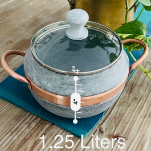 K&ouml;nnte beinhalten: Ein grauer Specksteintopf mit Kupferrand und Glasdeckel. Der Topf hat einen Holzgriff und misst 10 cm im Durchmesser. Er fasst 1,25 Liter.