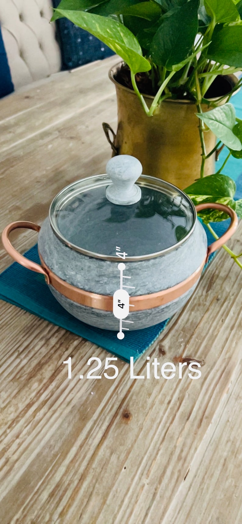 K&ouml;nnte beinhalten: Ein grauer Specksteintopf mit Kupferrand und Glasdeckel. Der Topf hat einen Holzgriff und misst 10 cm im Durchmesser. Er fasst 1,25 Liter.