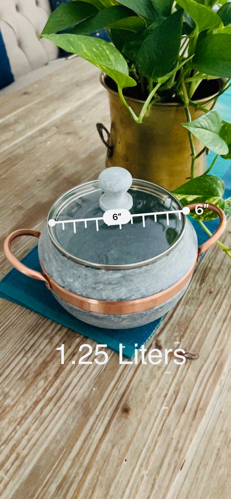 "A handcrafted soapstone pot with a transparent glass lid, showcasing its smooth, natural stone finish. The sturdy pot is designed for even heat retention, while the glass lid allows for easy monitoring of the cooking process."