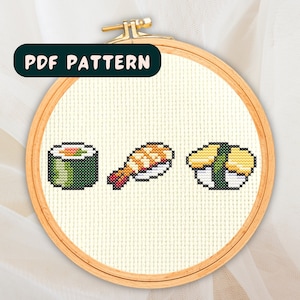 May include: A cross stitch pattern featuring three different types of sushi: a green maki roll, a nigiri with a shrimp topping, and a yellow tamago nigiri.