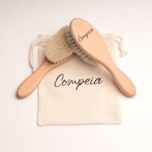 May include: Two wooden hair brushes with natural bristles in a white cotton drawstring bag. The brushes are labeled "Compeia".
