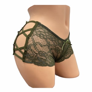 Puede incluir: Ropa interior de encaje verde oliva con un diseño entrecruzado en los laterales y un pequeño lazo en la parte delantera. La ropa interior está hecha de una delicada tela de encaje.