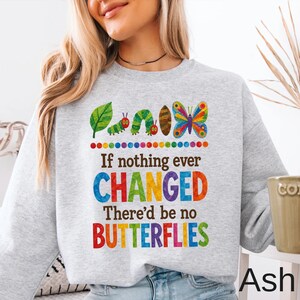 May include: A light gray crewneck sweatshirt featuring a colorful graphic of a green caterpillar, a brown cocoon, and a multi-colored butterfly. The text reads: If nothing ever CHANGED There'd be no BUTTERFLIES, with letters in various bright colors.