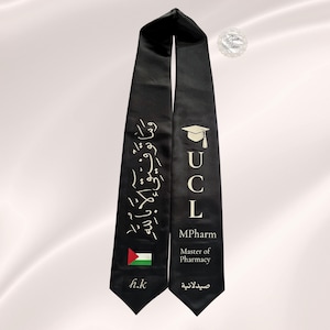 May include: A black graduation stole featuring white text and graphics. The left side displays Arabic calligraphy, a Palestinian flag, and the initials h.k. The right side features a graduation cap icon, the letters UCL, MPharm, Master of Pharmacy, and Arabic text.