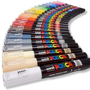 May include: A collection of Uni Posca PC-1M paint markers in various colors, arranged in a fan shape. The markers have black barrels with the brand name and model information printed on them. The caps are clear, and the tips are visible. The image is well-lit, showcasing the vibrant colors.