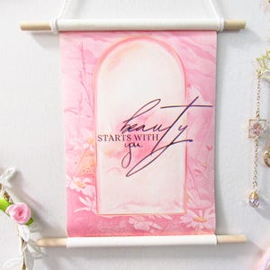 May include: Pink watercolor painting with a floral design and an archway. The text "beauty starts with you" is written in purple script.