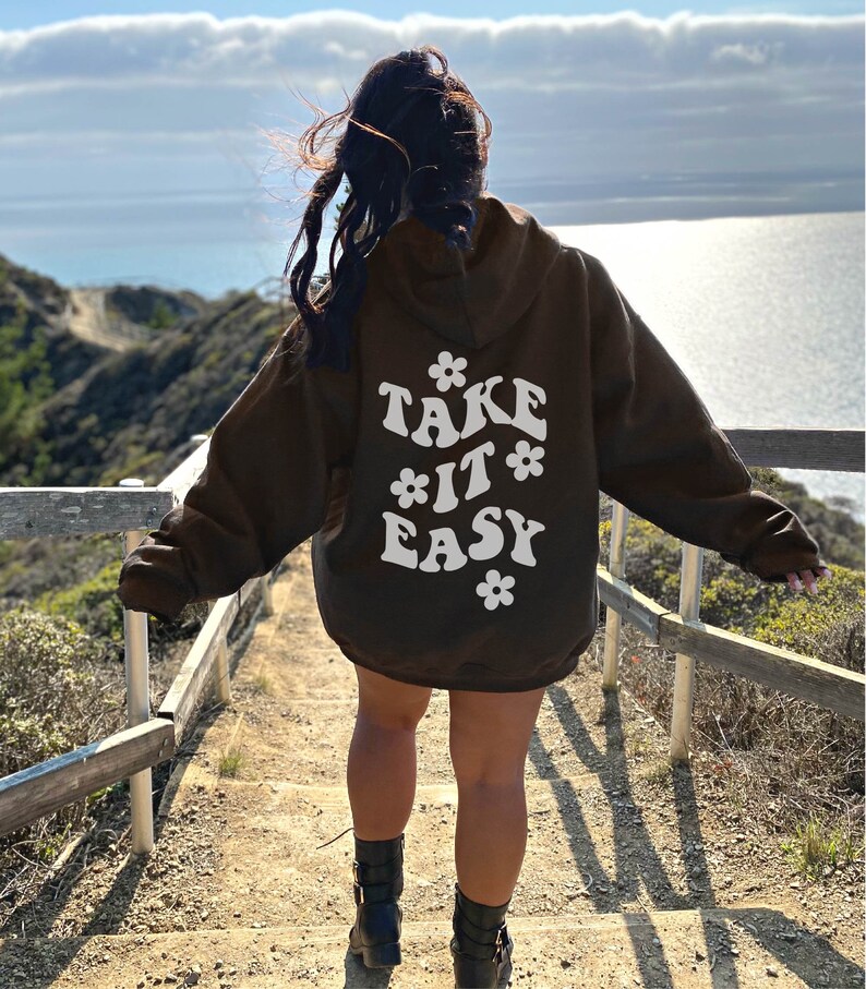 May include: A brown hoodie with a white graphic on the back that says "TAKE IT EASY" with stylized flowers around the text.