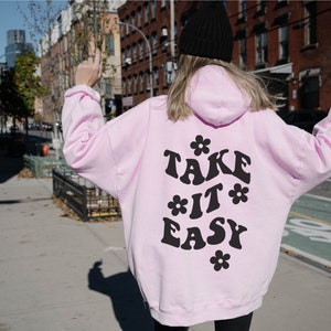 May include: Pink hoodie with a black graphic that says "TAKE IT EASY" with flowers around the text.