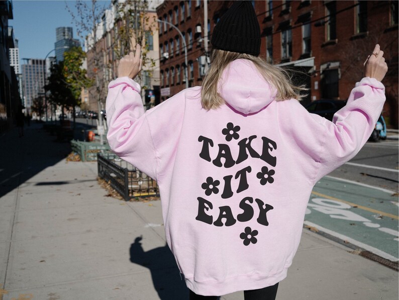 May include: Pink hoodie with a black graphic that says "TAKE IT EASY" with flowers around the text.