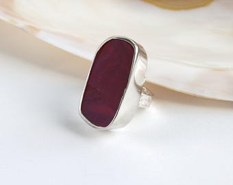 Può includere: Un anello d'argento con una grande pietra rettangolare di colore rosso scuro.