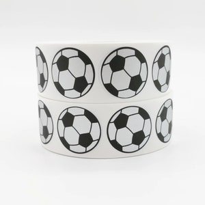 Puede incluir: Rollo de pegatinas blancas con diseños de balones de fútbol en blanco y negro.