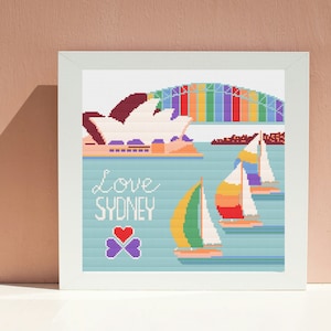 Könnte beinhalten: Kreuzstichmuster mit dem Opernhaus von Sydney, der Harbour Bridge von Sydney und Segelbooten. Der Text "Love Sydney" ist in Weiß mit einem lila Kleeblatt darunter geschrieben.