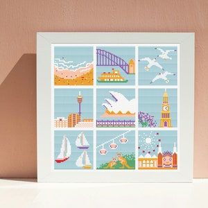 Op de afbeelding: Een kleurrijk kruissteekontwerp met iconische bezienswaardigheden van Sydney, Australië. Het ontwerp omvat het Sydney Opera House, de Sydney Harbour Bridge, de Sydney Tower en de veerboten. Het ontwerp is ingelijst in een wit frame.