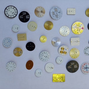 Peut inclure: Une collection de 28 cadrans de montre assortis, présentant divers motifs et couleurs. Les cadrans sont en métal et portent des chiffres romains, arabes et d'autres marques décoratives.