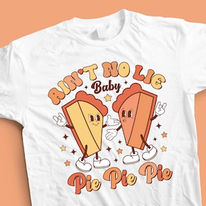 Puede incluir: Camiseta blanca con un diseño retro que presenta dos personajes de pastel con el texto "Ain't No Lie Baby Pie Pie Pie".