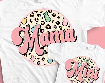 Puede incluir: Camisetas blancas con un diseño rosa y beige. El diseño presenta la palabra "Mama" en una camiseta y "Mini" en la otra, con un fondo de estampado de leopardo e ilustraciones de conejitos pastel.