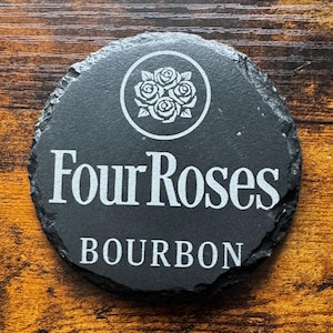 May include: A black slate coaster with a white logo of four roses in a circle and the text "Four Roses BOURBON".