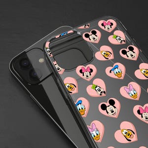 May include: A clear phone case with a pink and white heart pattern featuring Mickey Mouse, Minnie Mouse, Donald Duck, Goofy, and Pluto.