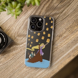 May include: A clear phone case with a black background and a design of Rapunzel and Flynn Rider in a boat with floating lanterns. The case has a cutout for the camera lens.