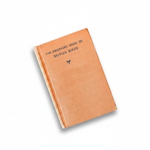 May include: A vintage book titled "The Observer's Book of British Birds" with a peach-colored cover. The book has a small black triangle symbol below the title. The book is set against a white background.