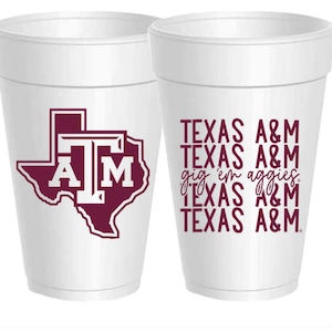 May include: Two white foam cups with a maroon Texas A&M logo. One cup features the Texas state outline with the letters "A&M" inside. The other cup has the text "TEXAS A&M" repeated four times with the phrase "gig 'em aggies" in between the second and third lines.