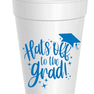 May include: White foam cup with a blue graduation cap and the text "Hats off to the grad!" printed on it.