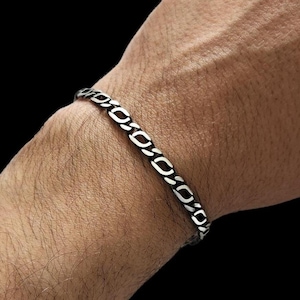 May include: A silver chain bracelet with a curb link design. The bracelet is on a person's wrist.