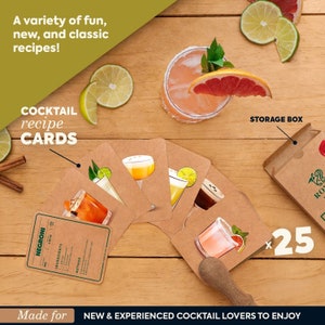 May include: A set of 25 cocktail recipe cards with illustrations of different cocktails. The cards are brown and have a white border. The text on the cards is in black. The cards are arranged in a fan shape on a wooden table. There is a storage box in the background. The text on the box says "STORAGE BOX".