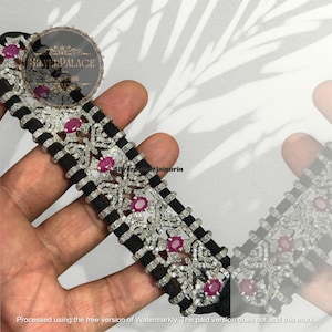 Può includere: Una collana girocollo nera e argento con pietre preziose color rubino e intricati disegni floreali. La collana presenta un motivo ripetuto di fasce nere e abbellimenti argentati. Il testo "SILVERPALACE Since 1986" è visibile.