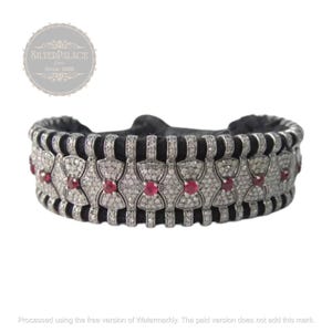 Può includere: Un braccialetto d'argento con una fascia in velluto nero e un design di fiori intrecciati incastonati con piccoli diamanti e rubini rossi.