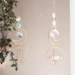Peut inclure: Deux capteurs solaires sur le thème céleste. Chacun présente un design en métal doré avec un croissant de lune, des perles de cristal et une sphère. L'un a une sphère de cristal multicolore, l'autre une sphère de cristal transparente.