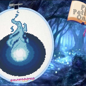 May include: A cross-stitch pattern of a blue flame in a black circle, with the text "@sewnerdubreich" at the bottom.