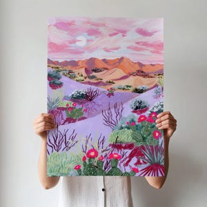 May include: A painting of a desert landscape with a pink sky, a sun, orange mountains, and purple sand dunes. The artwork depicts cacti with red flowers and various desert plants. The colour palette is warm and inviting.